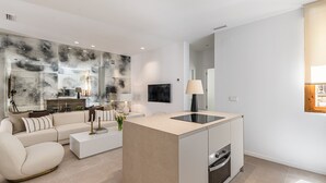 A modern living room with a sofa, coffee table, and a kitchen island with a built-in oven.