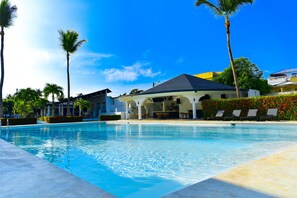 A swimming pool with lounge chairs and palm trees. - El Colibri Hotel (Sosúa)