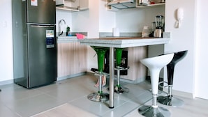 A modern kitchen with a built-in refrigerator, a bar counter, and two bar stools.