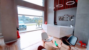 A modern reception area with a large desk, seating, and a view of the outside.