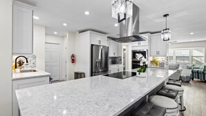 A modern kitchen with a large island, stainless steel appliances, and a chandelier. - Luxury Getaway | Saltwater Pool, Fire Pit & Games! (Bradenton)