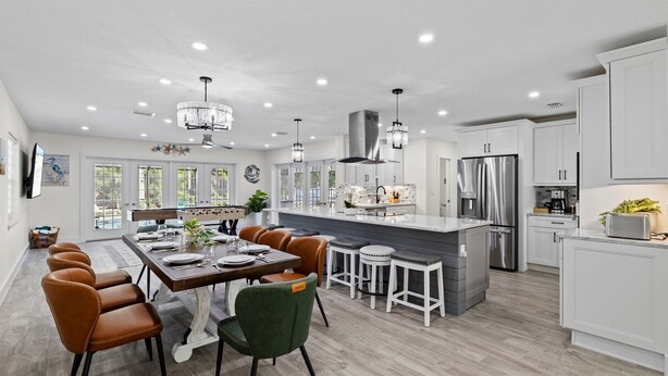 A modern kitchen with white cabinets, stainless steel appliances, and a large island. - Luxury Getaway | Saltwater Pool, Fire Pit & Games! (Bradenton)