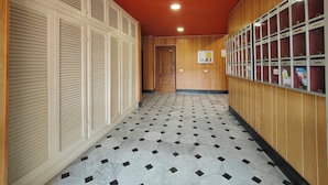 Un couloir avec des casiers, un tableau d’affichage et un sol à motifs.