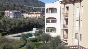 Un immeuble résidentiel à plusieurs étages, doté de balcons, d’une piscine et entouré de verdure.