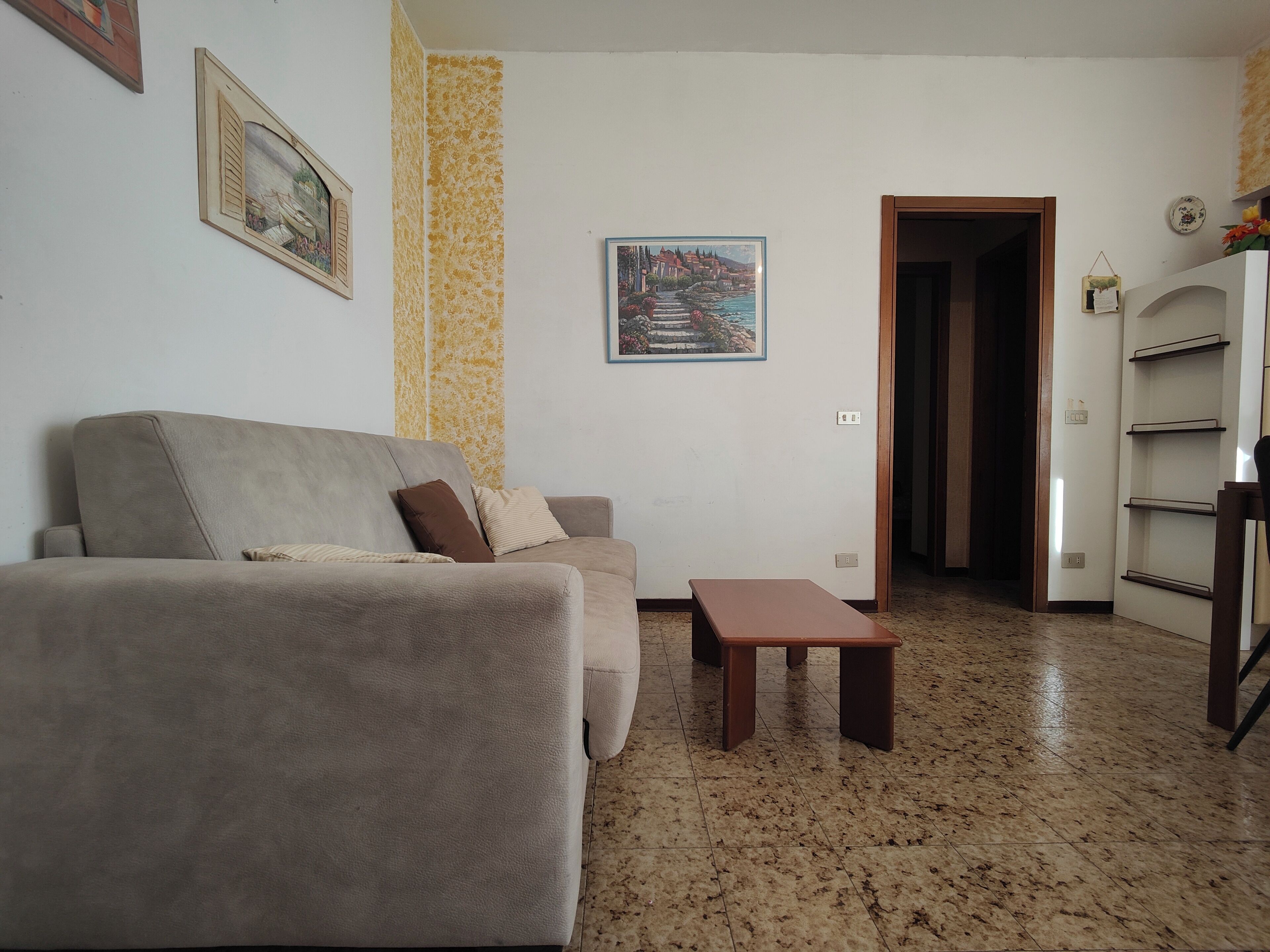 A living room with a sofa, a small table, and a painting on the wall.