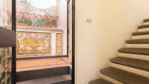 A staircase with a tiled wall and a view of a cityscape through a window.