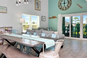 A dining area with a long table, chairs, and a clock on the wall. - Turtle Town: View | Private Pool | Screen Deck (Cape San Blas)