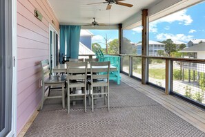 A covered porch with a table and chairs, a ceiling fan, and a view of the neighborhood. - Turtle Town: View | Private Pool | Screen Deck (Cape San Blas)