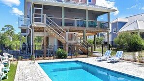Ein zweigeschossiges Haus mit Schwimmbad, überdachter Terrasse und umzäunter Hinterhof.