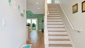 Eine Treppe führt zu einer zweiten Etage, mit einem Holzgeländer und weißen Wänden.