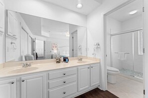 Un bagno moderno con un doppio lavabo, un ampio specchio, cabina doccia e un water.
