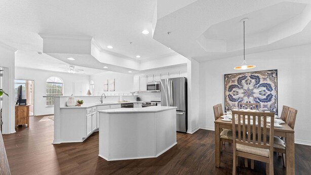 Een moderne keuken met witte kasten, een centraal eiland en een eetgedeelte met houten stoelen.