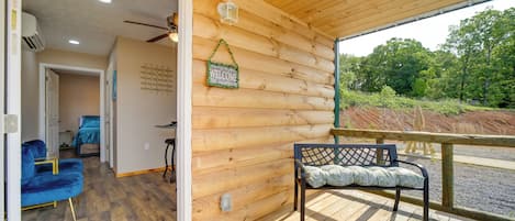 Interior de una cabaña de madera con un piso de tablas, un banco y una silla azul.