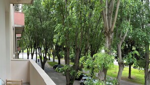 Varanda com vista para uma rua arborizada e carros estacionados.