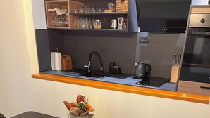 Cozinha moderna com uma mesa de jantar posta para dois, incluindo cafeteira, chaleira e diversos copos.