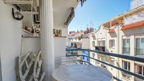 A balcony with a round table and chairs, overlooking a street with buildings.