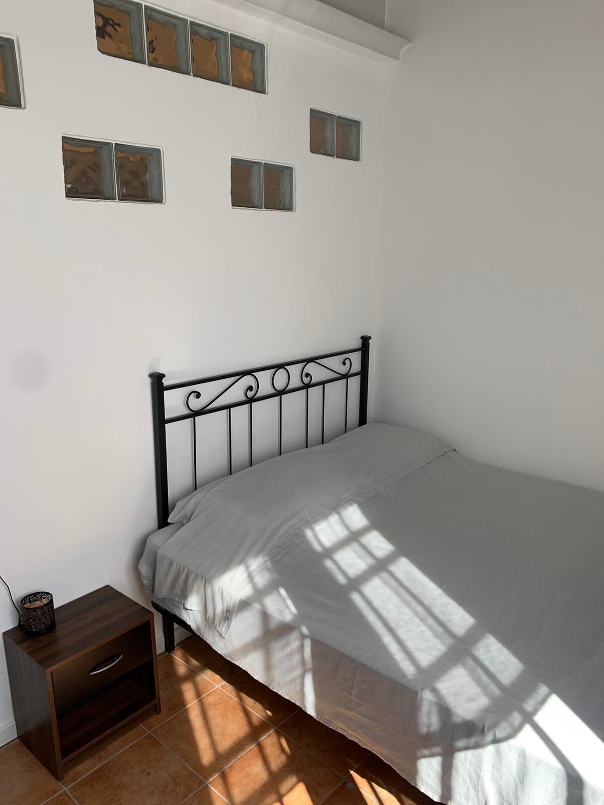 A bedroom with a bed, a nightstand, and a wall with abstract art.