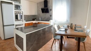 Una cocina moderna con una isla central, electrodomésticos integrados y un comedor con una mesa y sillas de madera.