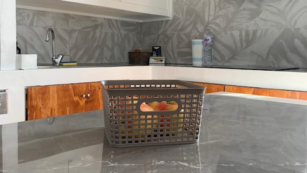 Una cocina moderna con encimera de mármol, horno empotrado y televisor montado en la pared.