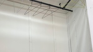 Una habitación con paredes blancas, una estantería negra y un tendedero.