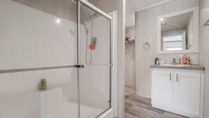 A modern bathroom with a glass shower enclosure, a vanity with a mirror, and a sink. - Redneck Riviera - Steinhatchee (Steinhatchee)