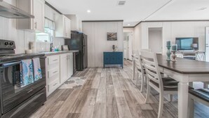 A modern kitchen with white cabinets, a black stove, and a blue cabinet in the center. - Redneck Riviera - Steinhatchee (Steinhatchee)