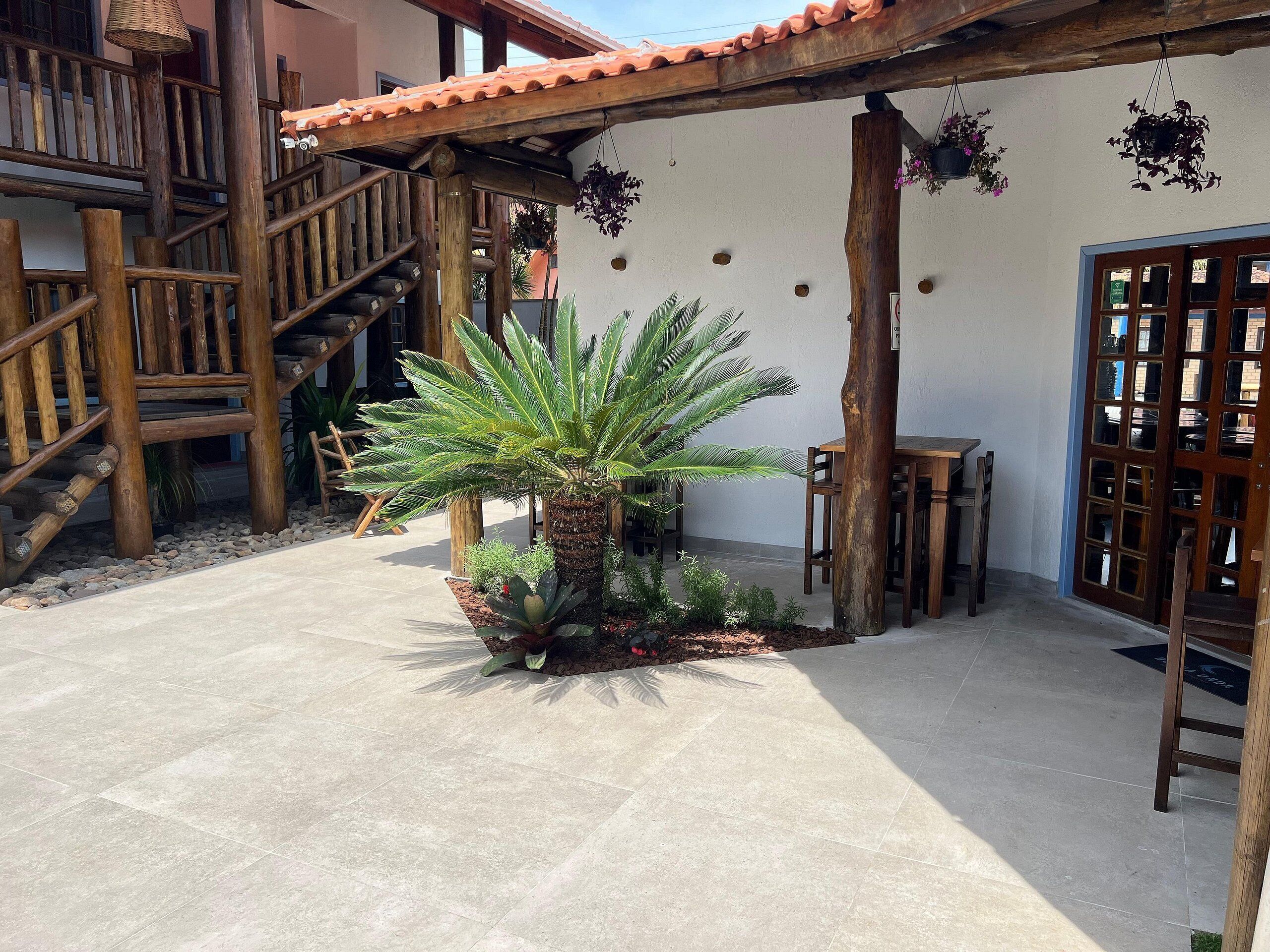 A courtyard with a palm tree, wooden staircase, and a wooden table under a pergola.