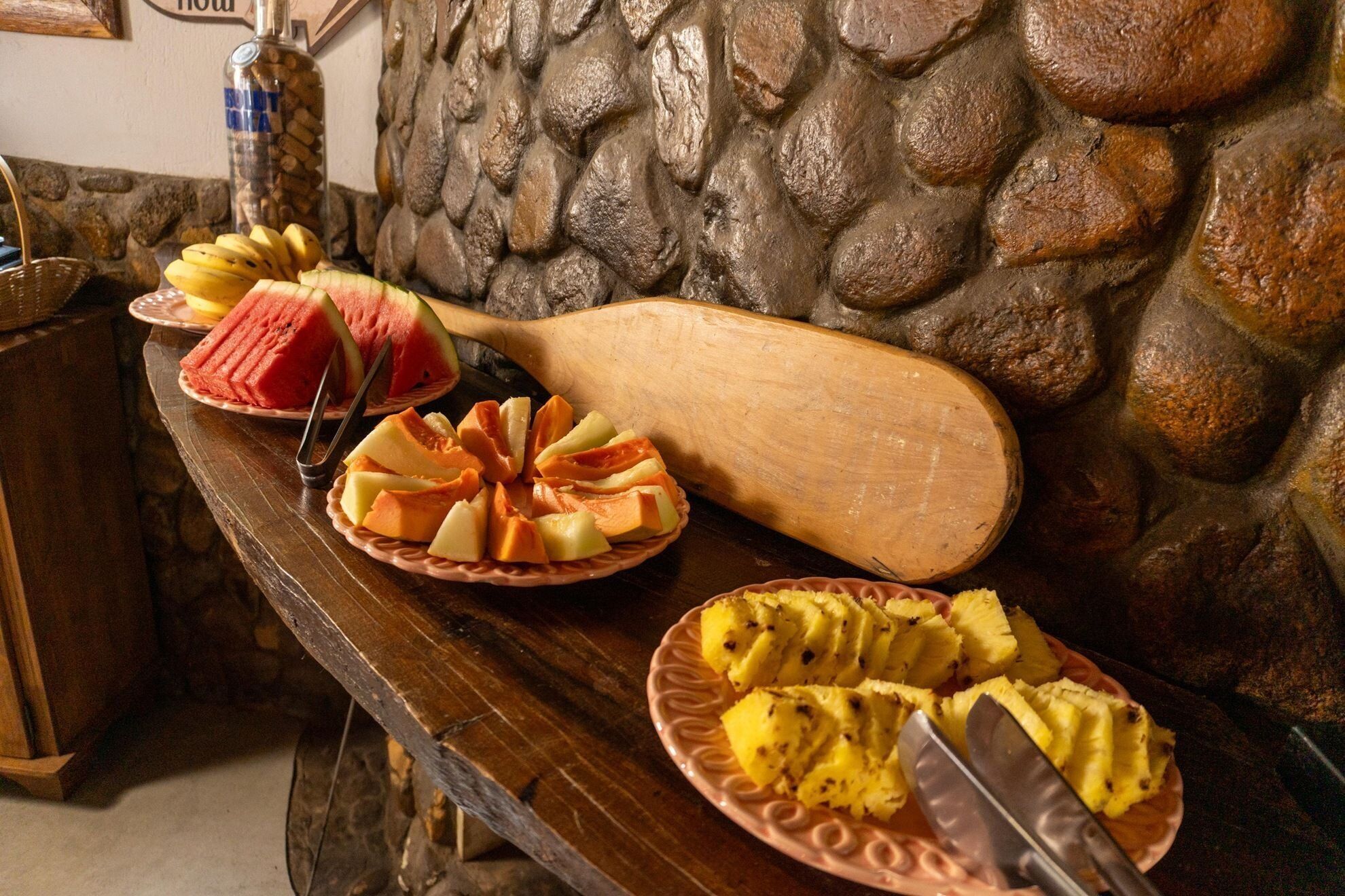 A buffet table with various fruits and a wooden paddle.