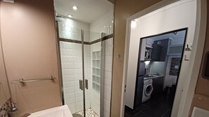 A modern bathroom with a glass-enclosed shower, a white sink, and a black tiled floor. - Beau Studio à 150 m de la mer Dans un Parc Privé ! (Six-Fours-les-Plages)