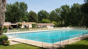 A rectangular swimming pool with a white fence, surrounded by a grassy area and trees. - Beau Studio à 150 m de la mer Dans un Parc Privé ! (Six-Fours-les-Plages)