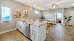 Une cuisine moderne dotée d’un grand îlot central, de luminaires suspendus et d’un ventilateur de plafond.