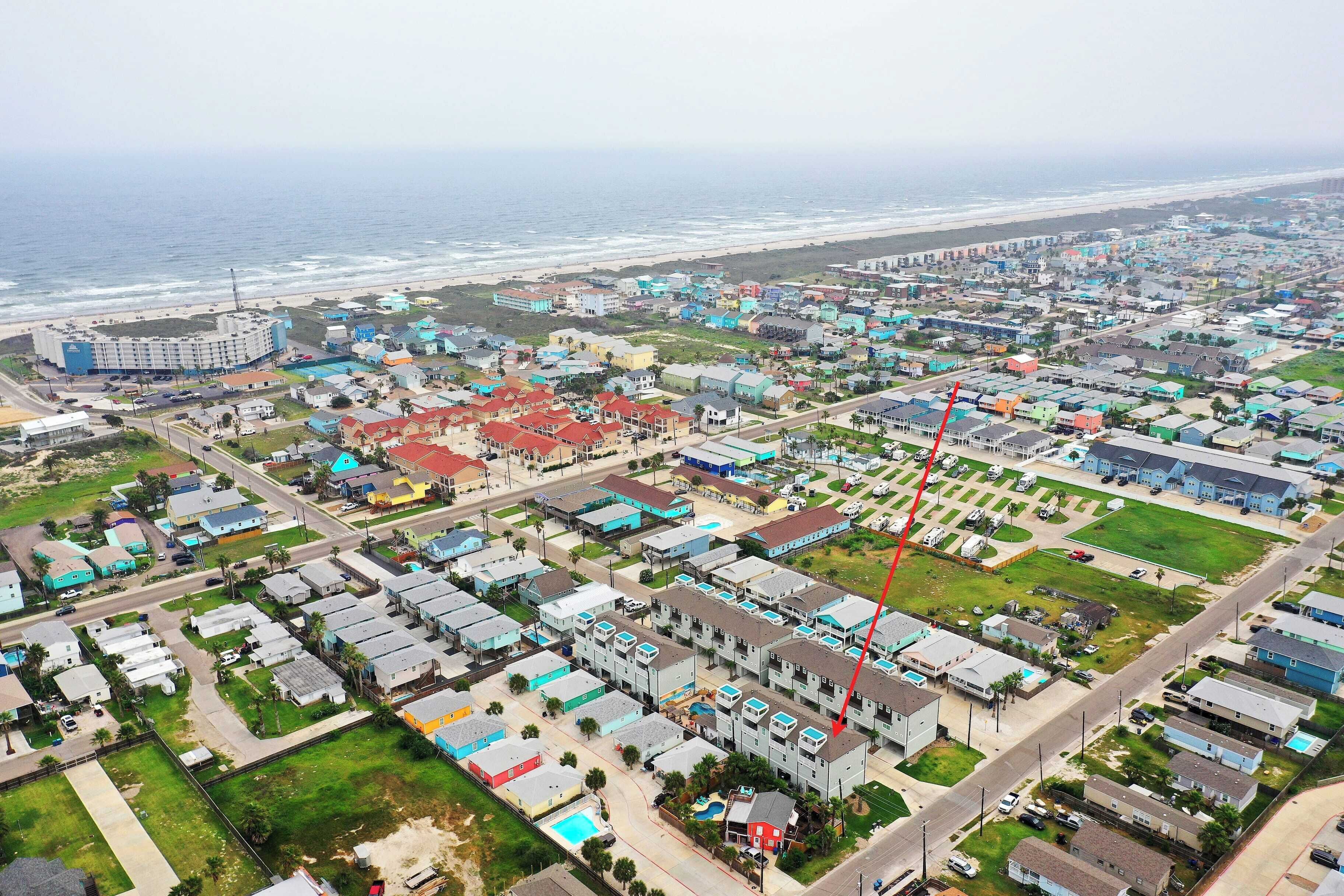 Vista aérea de una zona residencial costera con casas, una playa y un hotel grande.