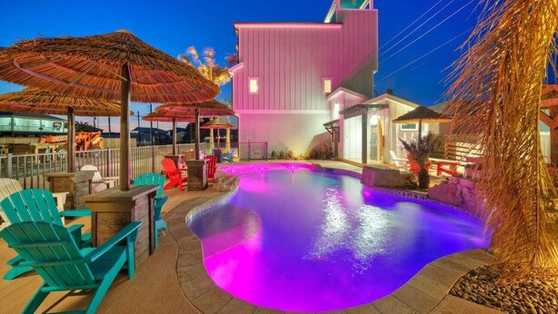 Une piscine à bord incurvé, entourée d’espaces de détente en plein air et de parasols.