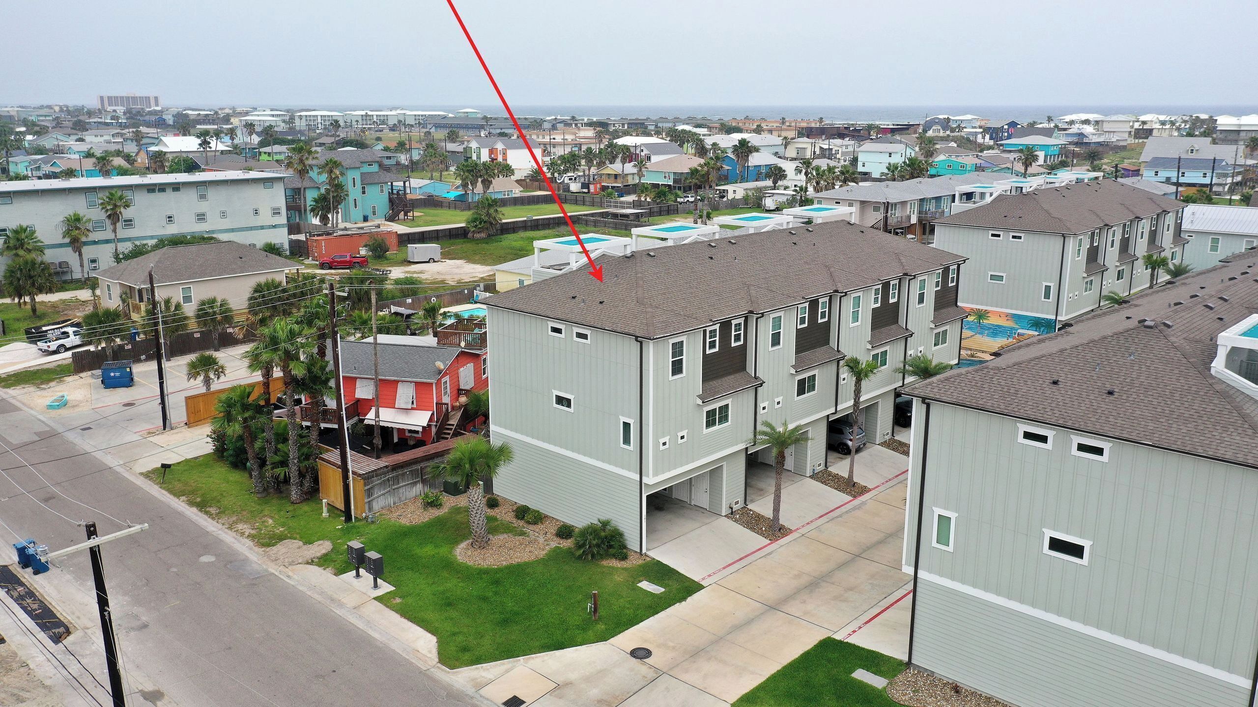 A multi-story residential building with a central courtyard, a swimming pool, and a view of the ocean.