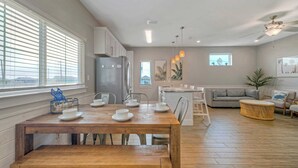 Une cuisine moderne avec une table à manger en bois, des meubles blancs et un réfrigérateur encastré.