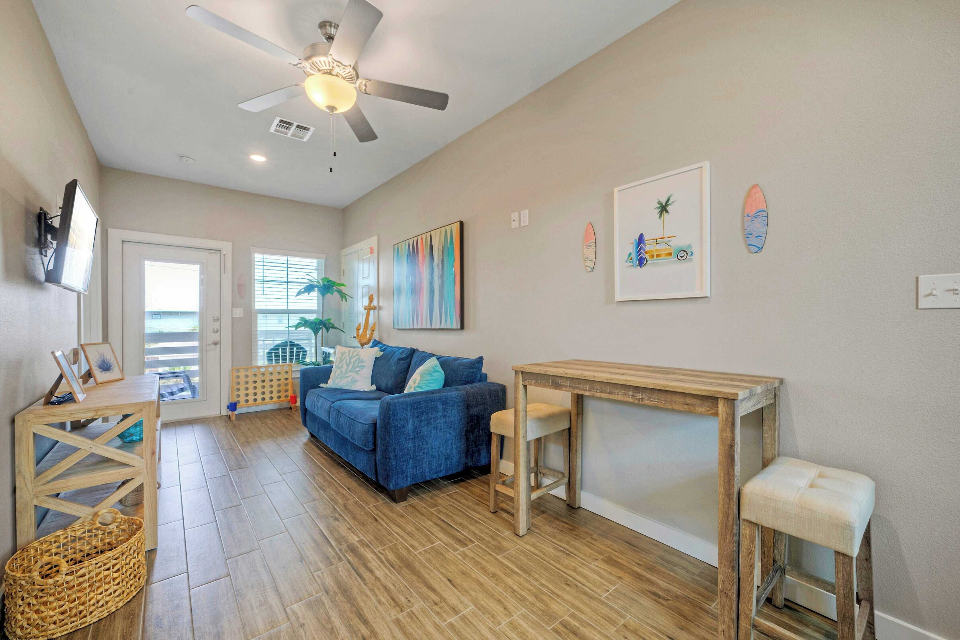 A living room with a blue sofa, wooden coffee table, and a ceiling fan.