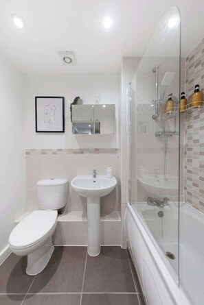 Bathroom features a pedestal sink, toilet, and glass-enclosed shower area.