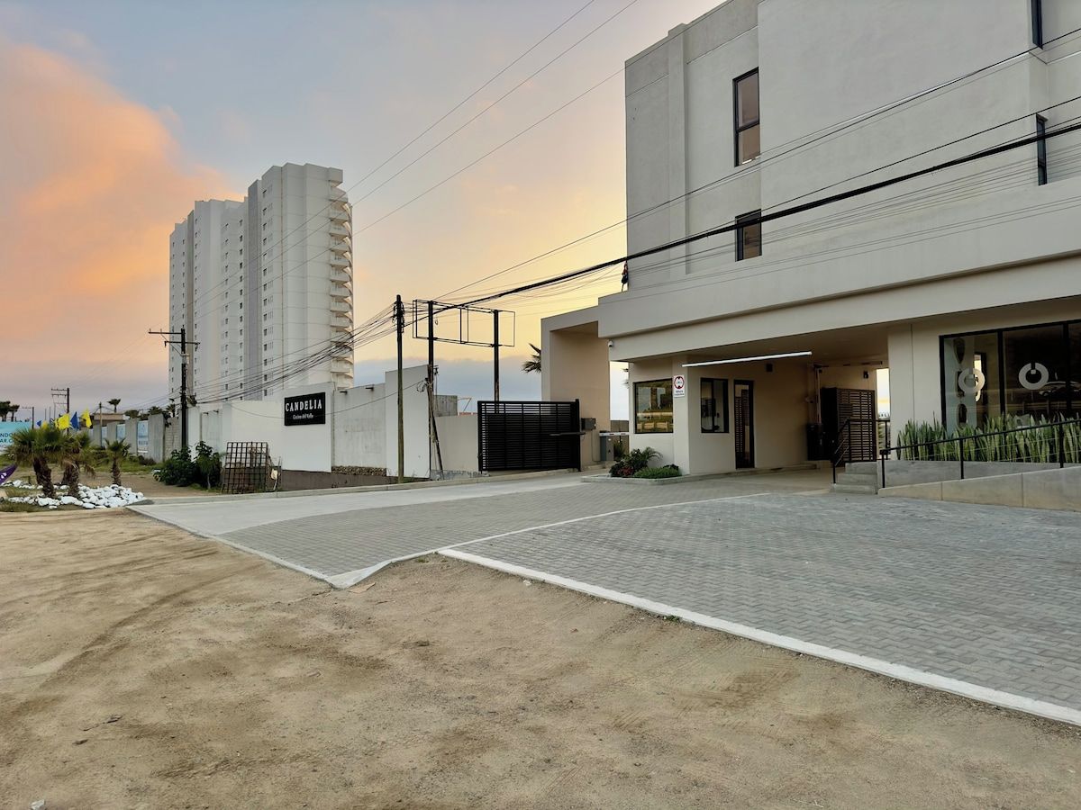 A modern building with a paved entrance and a sign indicating 'CANDELIA'.