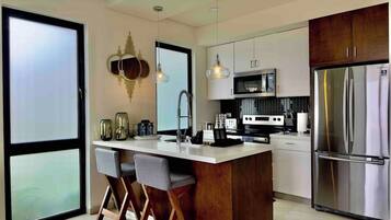 A modern kitchen with a central island, stainless steel appliances, and bar stools.