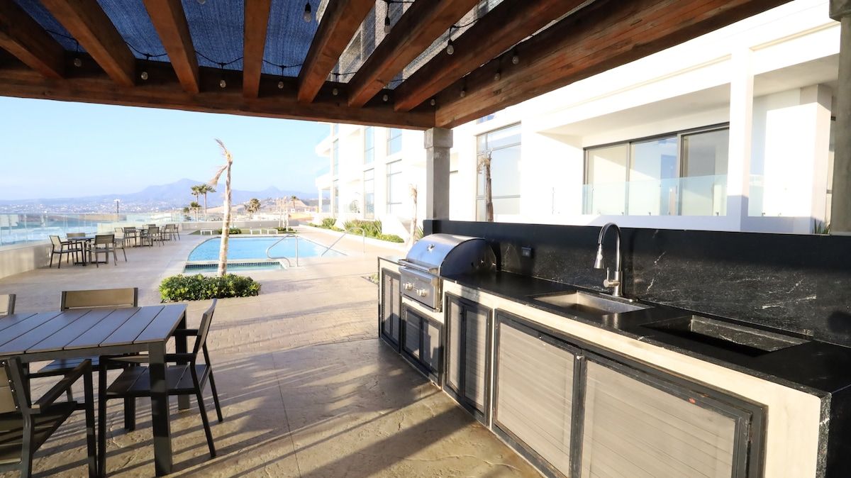 Un patio exterior con piscina, barbacoa y asientos.