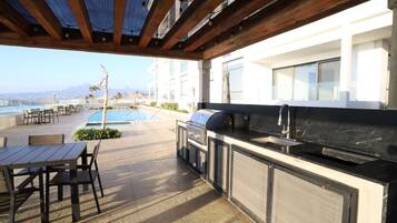 Un patio exterior con piscina, barbacoa y asientos.