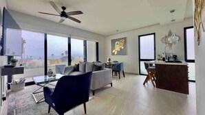 A modern living room with a sofa, armchair, and coffee table, a dining area with chairs, and a kitchen counter. - Mision Viejo Sur 1BR Apartment B103 (Playas de Rosarito)