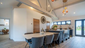 Una cocina moderna con una isla grande, armarios de madera y un comedor con mesa y sillas.