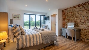 Un dormitorio con una cama grande, un escritorio, una silla, un televisor y una pared de piedra.