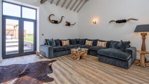 Una sala de estar moderna con un sofá modular, una mesa de centro de madera y una alfombra grande de cuero.