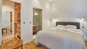 Une chambre avec un grand lit, un dressing et un espace douche.
