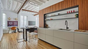 Une cuisine moderne avec un plancher en bois, des meubles blancs et un meuble-bar intégré pour les bouteilles de vin.