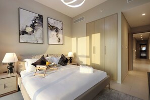 A modern hotel bedroom with a large bed, bedside tables, a wardrobe, and abstract art on the wall.