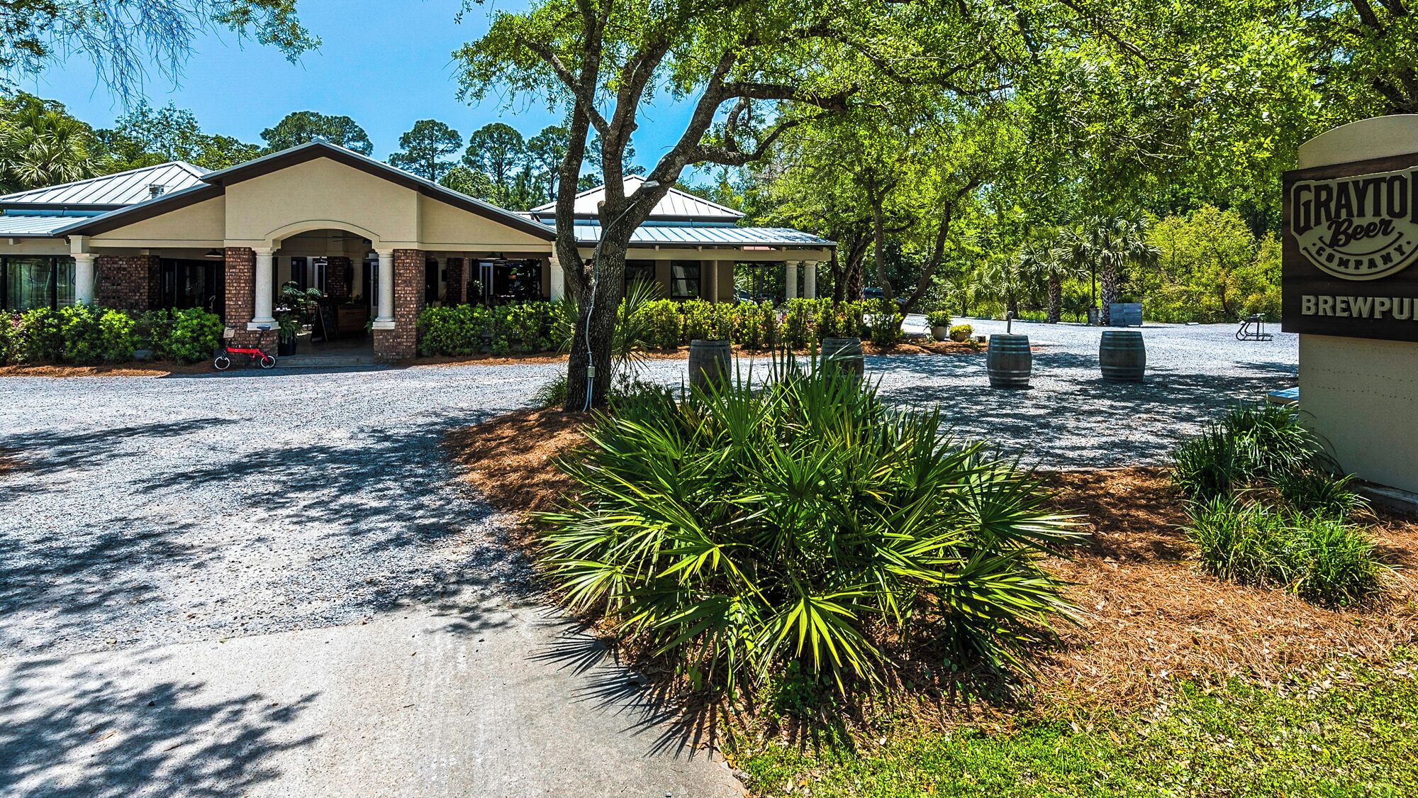 A building with a covered entrance, a gravel driveway, and a sign for Grattol Beer Company.