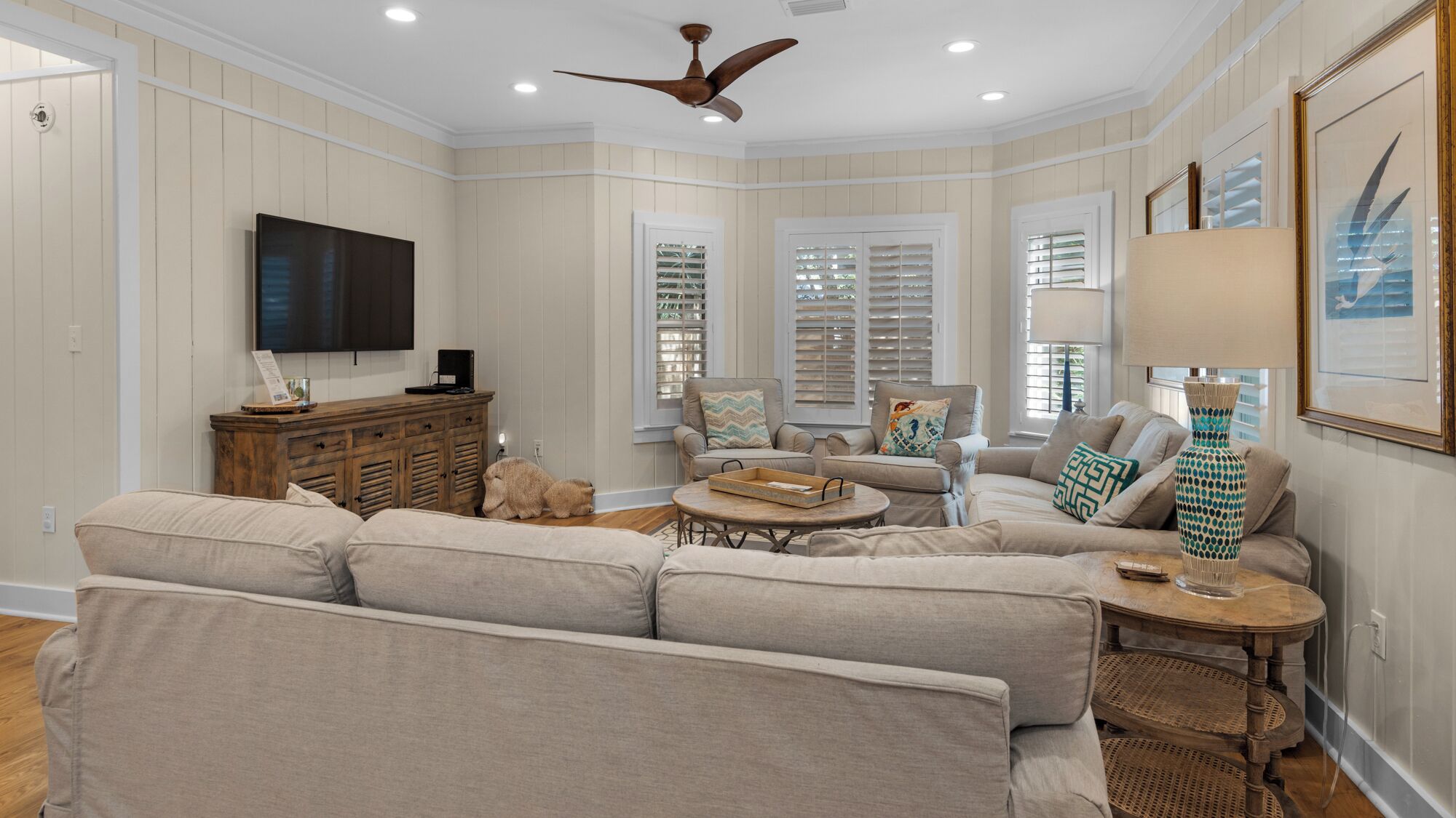 A spacious living room with a large sectional sofa, a wooden coffee table, and a ceiling fan.